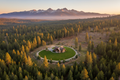 Aerial drone view of a forest with defensible space clearing around a rural home with Sierra Nevada mountains in background
